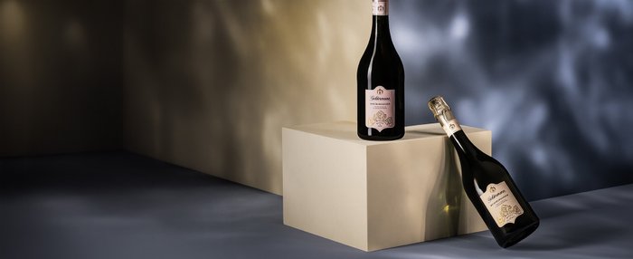 Die Flasche Sekt auf dem Podest strahlt Eleganz aus, während die andere Flasche leicht geneigt daneben liegt.