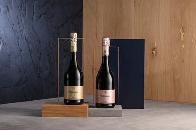 Ein minimalistisches Arrangement zeigt zwei Sektflaschen, die in einem modernen Raum mit Holz- und Betonelementen platziert sind.