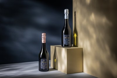 Eine Flasche Cremant mit silbernen und eine Flasche Cremant mit goldenem Verschluss, beide stilvoll präsentiert
