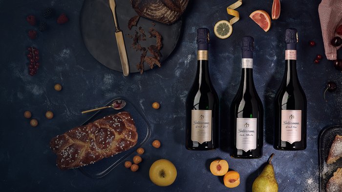 Ein elegantes Arrangement mit Sektflaschen, frischen Früchten und einem rustikalen Brot, das eine festliche Stimmung vermittelt.