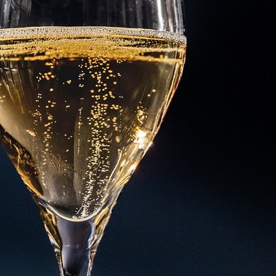 Das Glas zeigt feine Bläschen, die an die Oberfläche steigen, und reflektiert das Licht in einem stilvollen Ambiente.