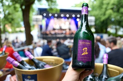 Die elegante Flasche der Bayreuther Festspiel-Cuvée 2026 vor der Kulisse des Festspielparks