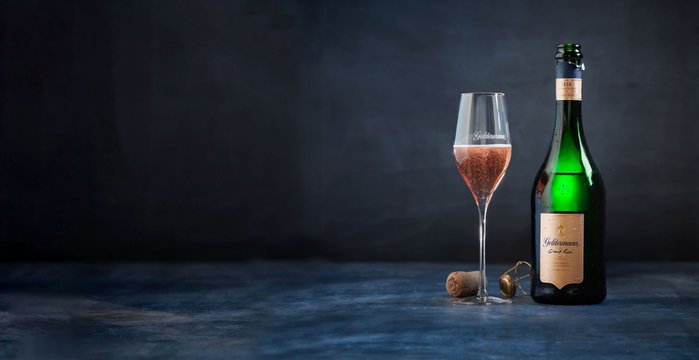 Die Flasche Sekt mit goldenen Etiketten und ein Glas mit sprudelndem Inhalt strahlen Luxus und Feierlichkeit aus.