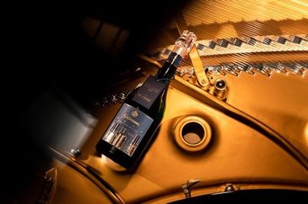 Die Flasche Champagner, umgeben von goldenen Klavierteilen, strahlt Luxus und Feierlichkeit aus, während das Licht sanft reflektiert.