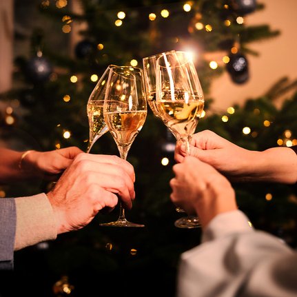 Weihnachtsgeschenk-Ideen: Anstoßen mit vier Gläsern Geldermann Sekt vor dem Weihnachtsbaum