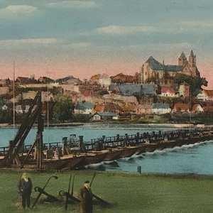 Eine malerische Landschaft mit einem Fluss, einer Holzbrücke und einer Stadt im Hintergrund, die von sanften Hügeln umgeben ist.
