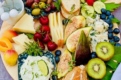 Ein reichhaltiges Käse- und Obstbrett mit verschiedenen Käsesorten, frischen Früchten und knusprigem Brot, perfekt für einen Snack.