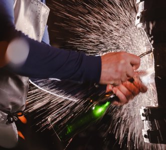 Eine gruene Flasche wird gekoepft, man sieht noch die Hand eines Arbeiters