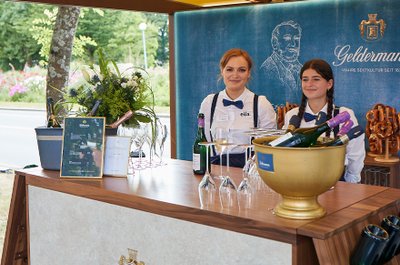 Der Getränkestand bietet eine Auswahl an Sektflaschen und Gläsern, während die beiden Damen freundlich lächeln.