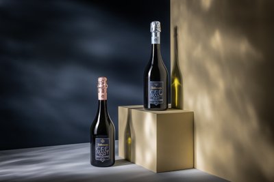 Eine Flasche Cremant mit silbernen und eine Flasche Cremant mit goldenem Verschluss, beide stilvoll präsentiert