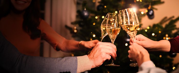 Sliderbild zu Weihnachtsgeschenk-Ideen: Anstoßen mit vier Gläsern Geldermann Sekt vor dem Weihnachtsbaum