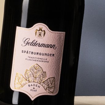 Eine Flasche Geldermann Spätburgunder mit einem eleganten, rosafarbenen Etikett und goldenen Blattmotiven.