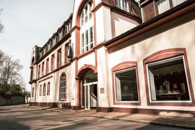Ein historisches Gebäude mit einer eleganten Fassade in sanften Farben, das an einer ruhigen Straße steht.