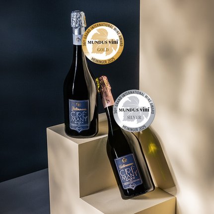 Zwei Flaschen Crémant stehen auf einem hellen Podest, eine mit goldener und die andere mit silberner Auszeichnung versehen.