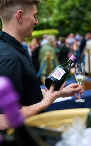 Ein junger Mann schenkt die Bayreuther Festspiel Cuvée 2025 in ein Sektglas ein.