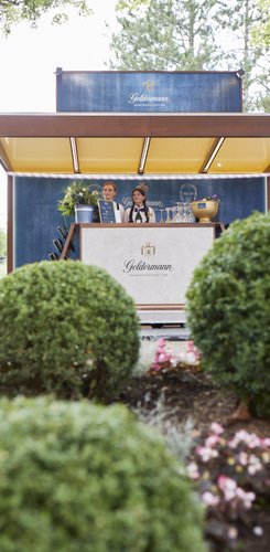 Der Getränkestand von Geldermann zeigt zwei freundliche Mitarbeiterinnen, die bereit sind, Gäste mit Getränken zu bedienen.