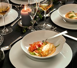 Ein elegantes Abendessen mit einem Teller, der zarte Fischfilets und Hummer auf einer cremigen Sauce präsentiert.