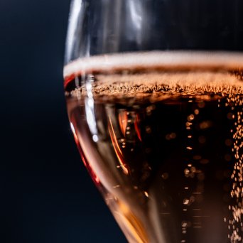 Nahaufnahme eines Weinglases mit rosanem Prickelwein