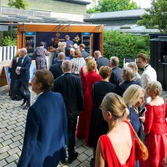 Besuchende der Bayreuther Festspiele 2025 stehen vor dem Geldermann Sektstand