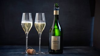 Die Flasche Geldermann Grand Brut ist geöffnet, während zwei Gläser mit prickelndem Sekt bereit zum Anstoßen sind.