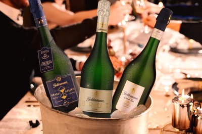 Geldermann Festtagspaket: Je eine Flasche Grande Réserve, Grand Rosé und Jahrgangssekt Brut 2020 in einem Sektkühler auf einem festlich gedeckten Tisch