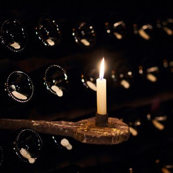 Eine brennende Kerze vor einem Rüttelpult mit Geldermann Sektflaschen