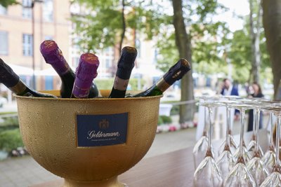 Der Sektkühler aus Gold zeigt feuchte Flaschen mit bunten Kapseln, während elegante Gläser bereitstehen, um angestoßen zu werden.
