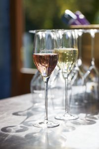 Ein elegantes Glas mit roséfarbenem Sekt steht im Vordergrund, während ein weiteres Glas mit weißem Sekt im Hintergrund sichtbar ist.