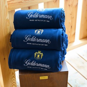 Geldermann Soirée Rosé: Ein Stapel dunkelblauer Fleece-Decken mit Geldermann-Logo