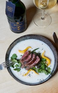 Ein elegantes Gericht mit zartem Rindfleisch, umgeben von einer cremigen Sauce und frischen Kräutern auf einem rustikalen Tisch.