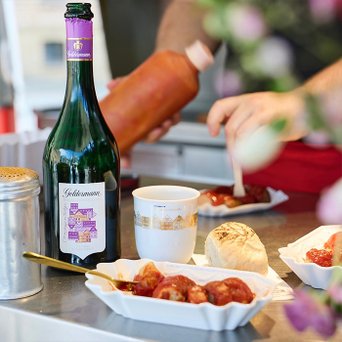 Eine Flasche der Geldermann Bayreuther Festspiel Cuvée 2025 auf einem Tisch mit Essen