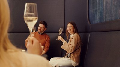 Ein fröhlicher Moment zwischen Freunden, die in einer modernen Lounge anstoßen und die Gesellschaft des anderen genießen.