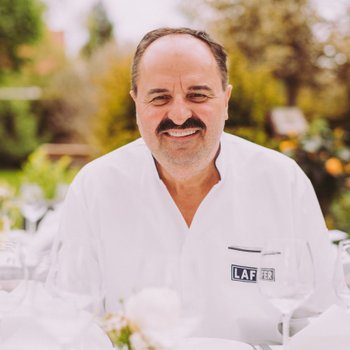 Johann Lafer sitzt im Garten am Tisch mit Geldermann-Sekt