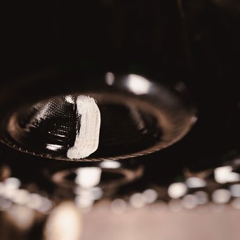 Die untere Perspektive von glänzenden Flaschen, die in der Dunkelheit hängen, mit einem markanten weißen Strich, der die Aufmerksamkeit auf sich zieht.