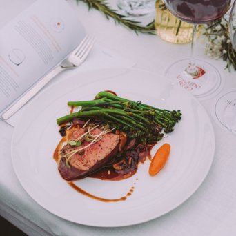 Ein elegantes Gericht mit zartem Fleisch, frischem Gemüse und einer aromatischen Sauce auf einem weißen Teller serviert.
