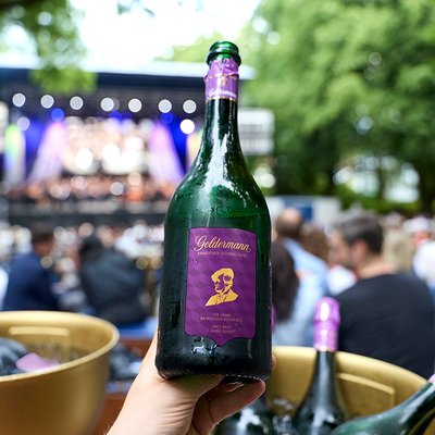 Eine Flasche der Geldermann Bayreuther Festspiel Cuvée 2026 vor der Kulisse der Bayreuther Festspiele